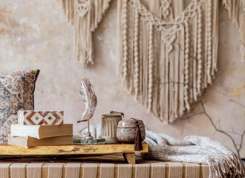 Modern oriental living room with design beige chaise longue, beautiful macrame, pillows, wooden tray, book, decoration and elegant personal accessories in home decor.